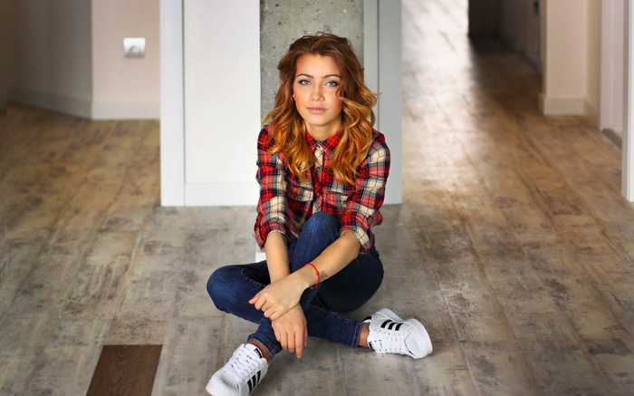 Woman in plaid shirt and jeans sitting on floor