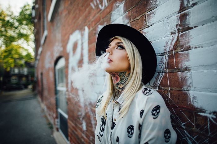 Madison Skye smoking in front of a brick wall