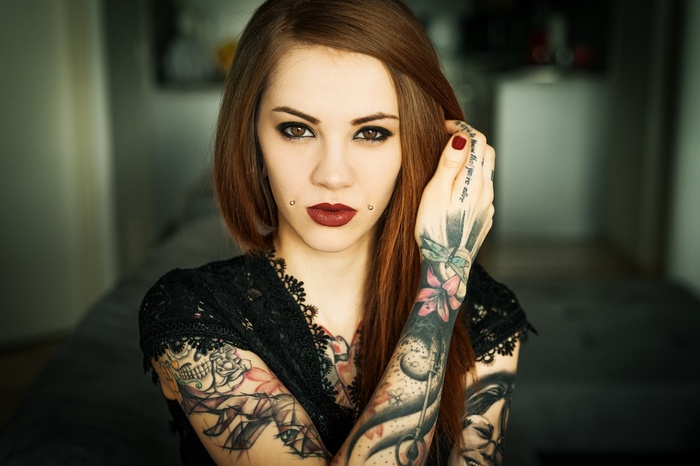 Woman with tattoos and piercings looking at viewer