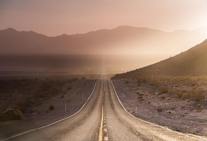 Desert road leading to mountains at sunset in Nevada