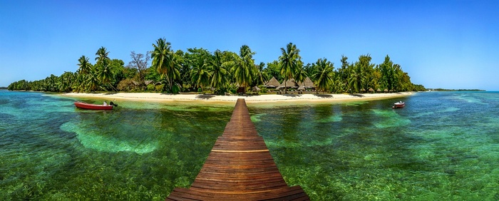 Tropical island with palm trees, beach, and a wooden dock