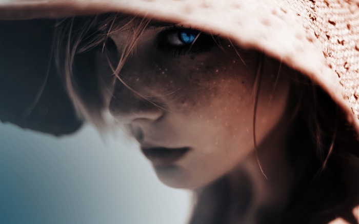 Close-up of a girl with blue eyes wearing a hat