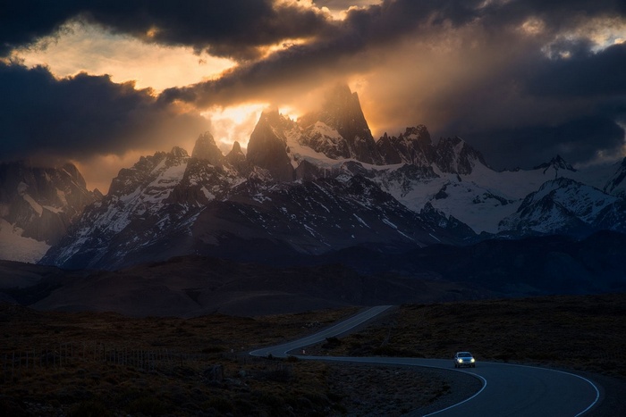 Car driving on a road towards snowy mountains at sunset in Patagonia