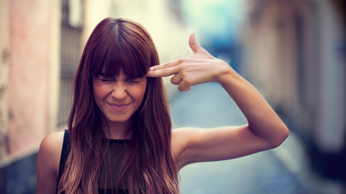 Woman making a finger gun gesture to her head