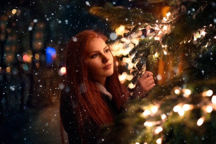 Redhead woman with long hair near Christmas tree lights