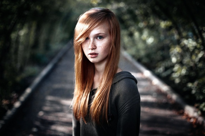 Young redhead girl with freckles in a forest