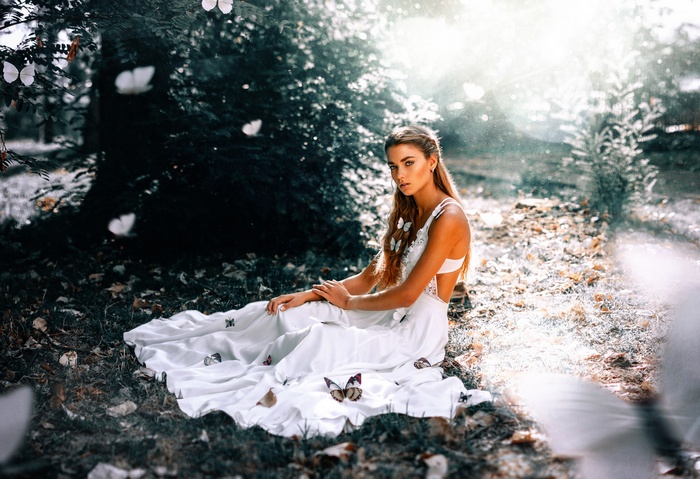 Woman in white dress with butterflies in forest