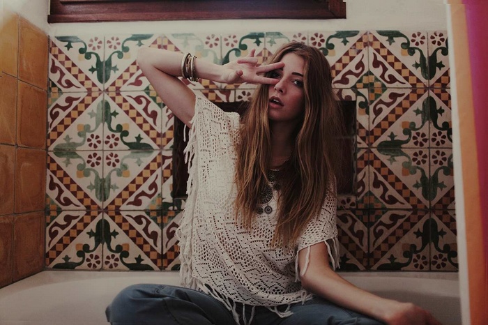 Woman in poncho sitting and making peace sign