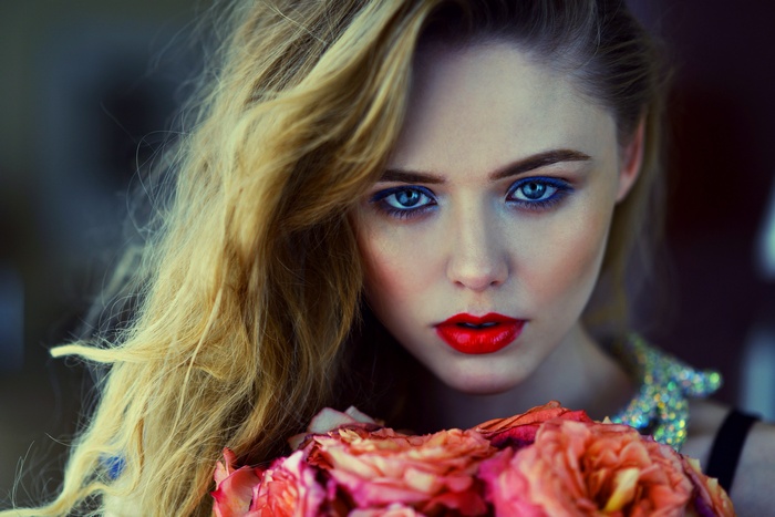 Woman with blue eyes and red lipstick holding flowers