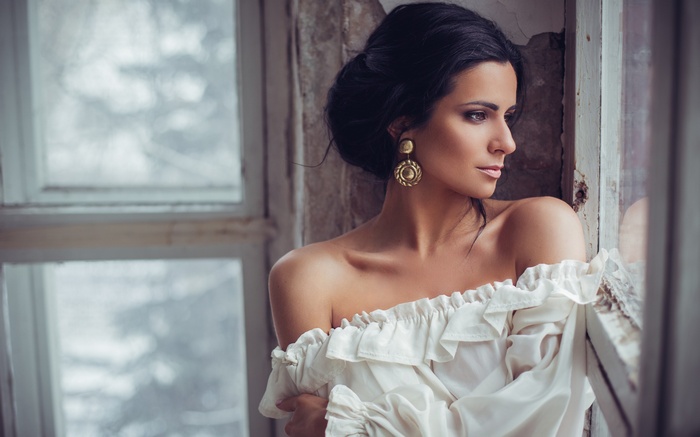 Woman with bare shoulders looking out a window