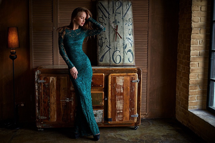 Woman in a green dress by a clock