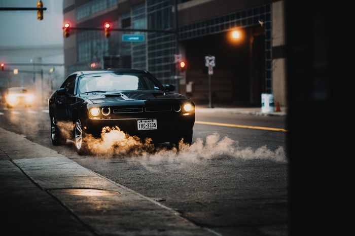 Black Dodge Challenger doing a burnout in the city
