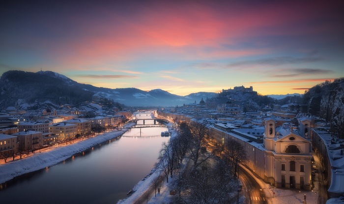 Salzburg cityscape with river and mountains at sunset in winter