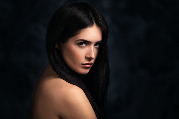 Woman with long black hair looking over her shoulder