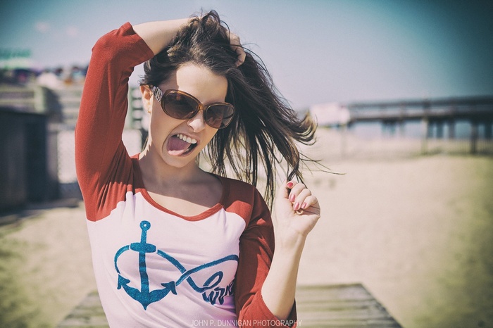 Woman with sunglasses sticking tongue out at the beach