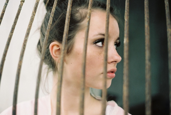 Woman with freckles behind bars