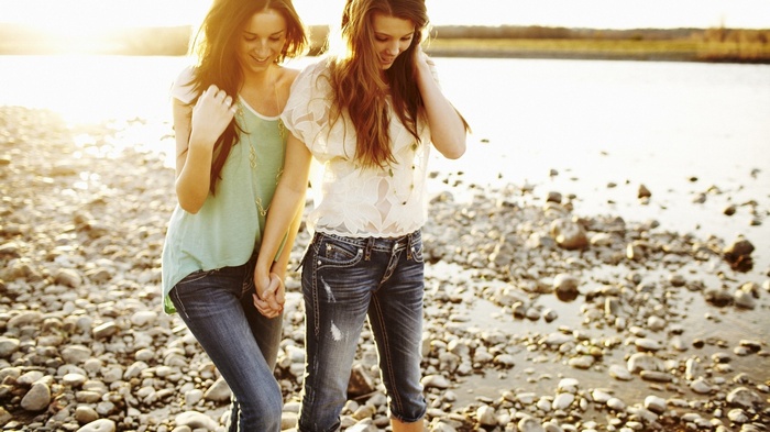 Two women holding hands by the water