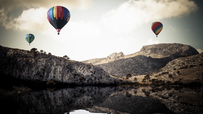Hot air balloons over a lake and mountains