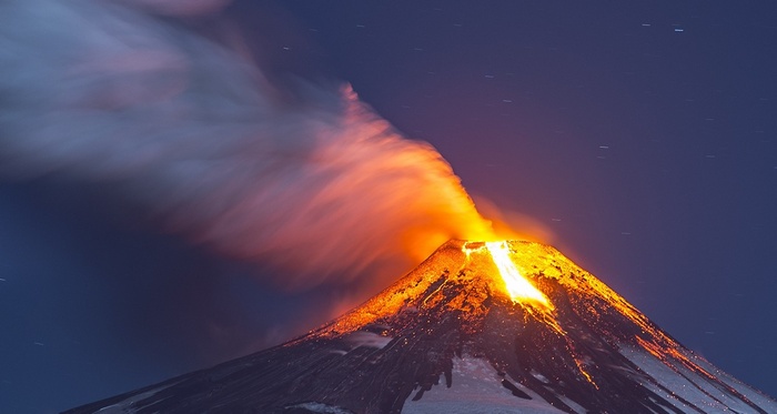 Volcano eruption with lava and smoke under a starry night sky