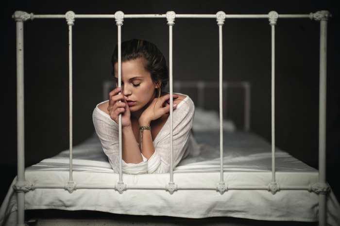 Woman lying on a bed behind bars