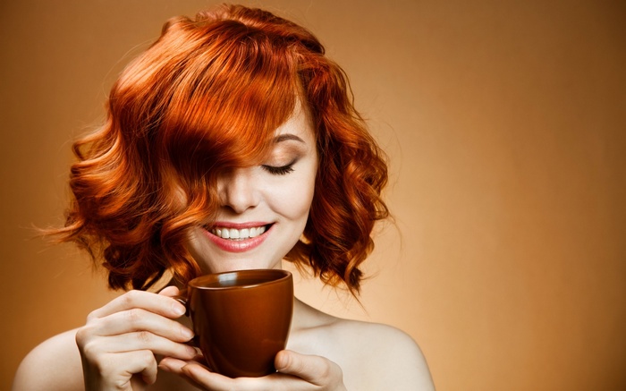 Woman with red curly hair holding a coffee cup