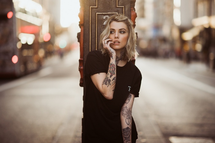 Woman with blonde hair and tattoos in a city street