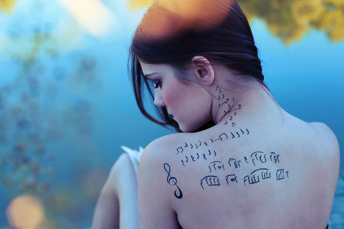 Woman with musical notes tattoo on her back
