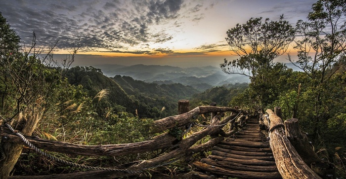 Wooden walkway through misty mountains at sunset in Taiwan