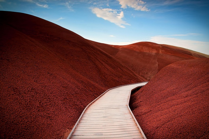 Wooden boardwalk through red desert hills