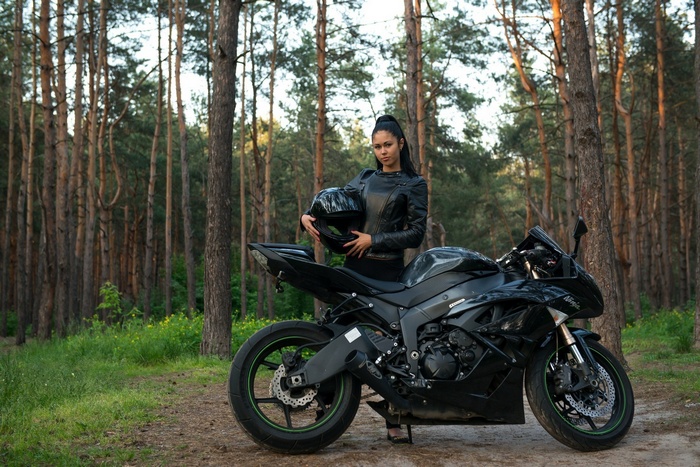 Woman with Kawasaki Ninja motorcycle in forest