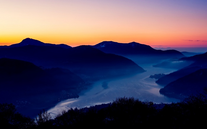 Mountains and lake at sunset with fog
