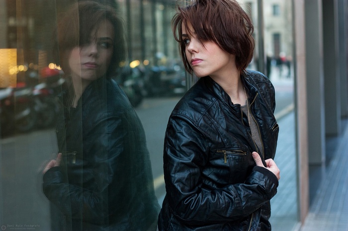 Woman with pierced nose in leather jacket reflected in glass