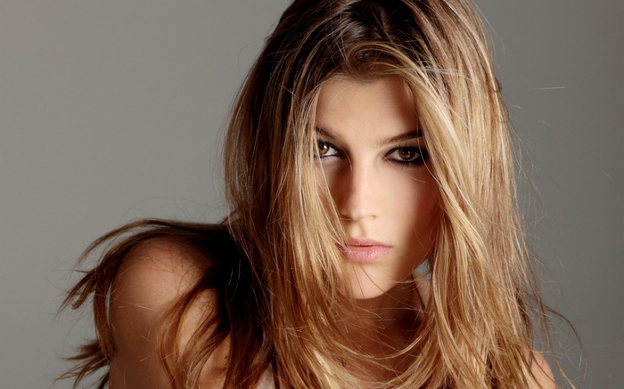 Woman with long blonde hair and dark eye makeup