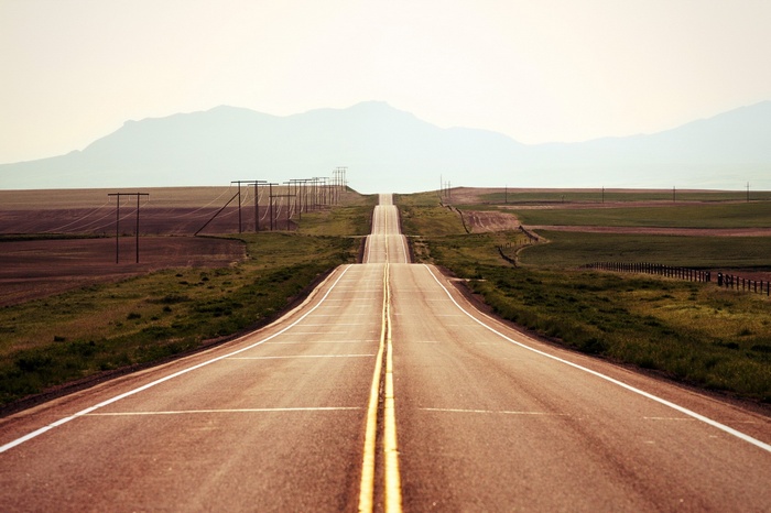 A long, empty road stretching towards distant mountains