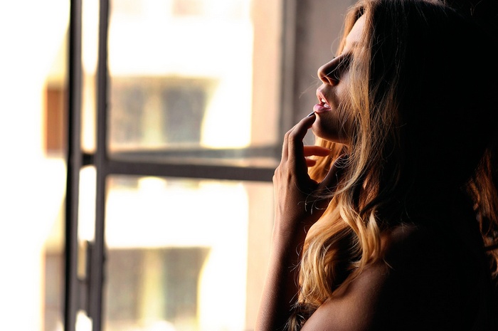Woman with hand on chin by window