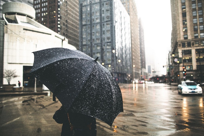 Person holding umbrella in the rain in a city