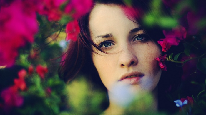 Woman with blue eyes and freckles among flowers