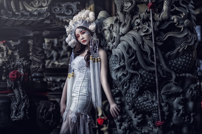 Woman in traditional Asian attire with dragon sculpture