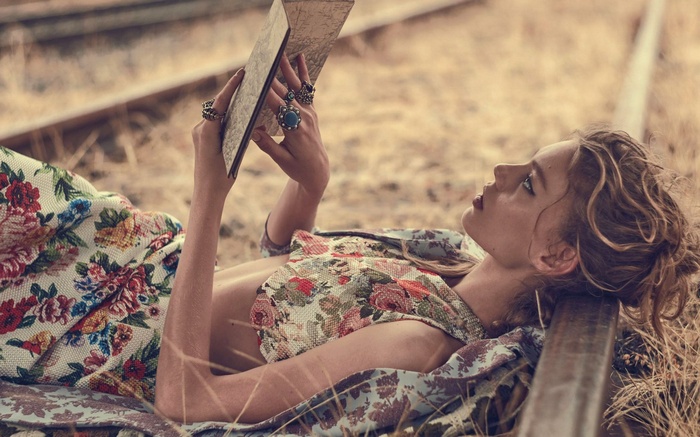 Woman reading a book on train tracks
