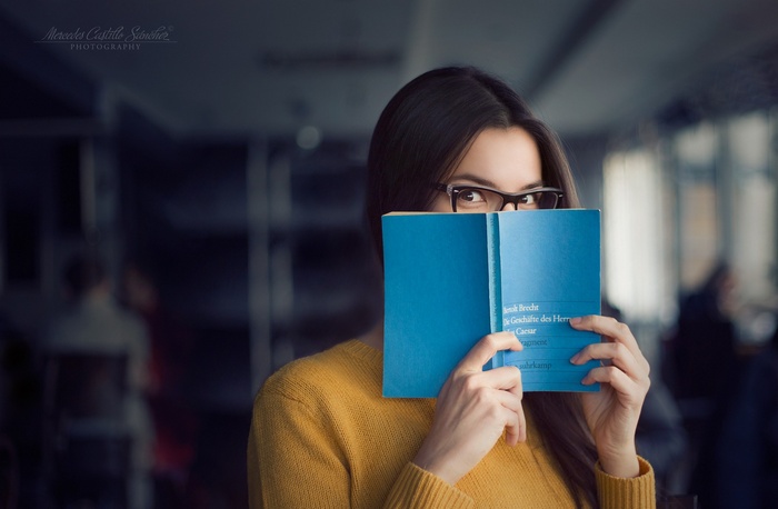 Woman in glasses reading a blue book