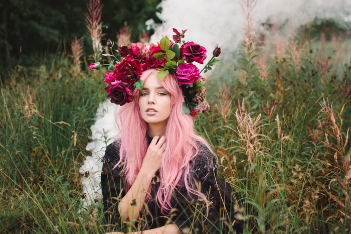 Woman with pink hair and flower wreath in field