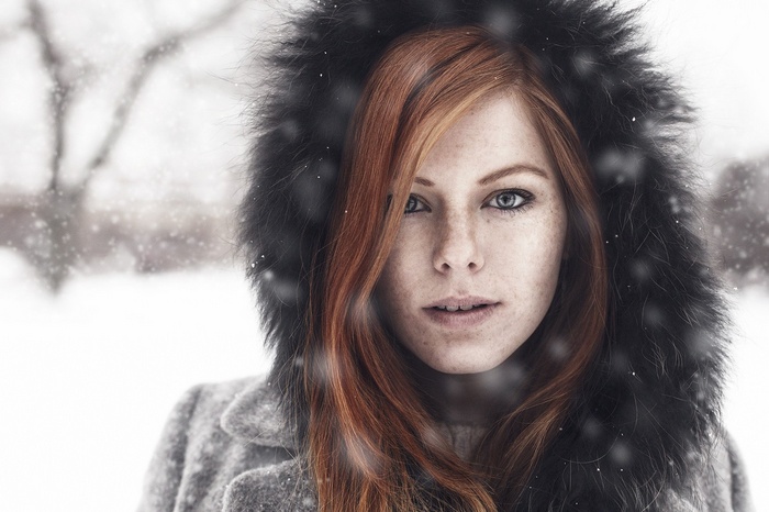 Redhead woman in a fur-hooded coat in the snow