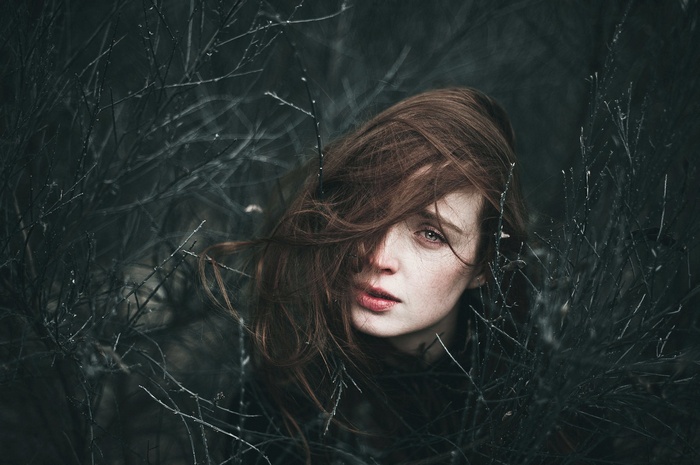 Woman with red hair among dark twigs