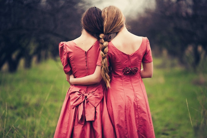 Two women in red dresses with braided hair