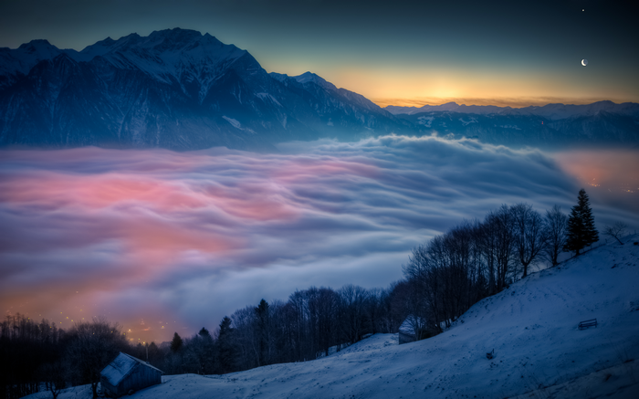 Snowy mountains above a sea of clouds at dusk