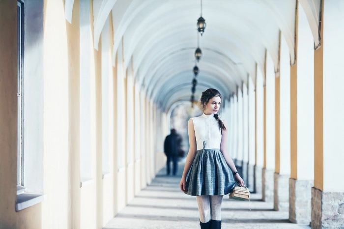 Woman with books in an arched hallway