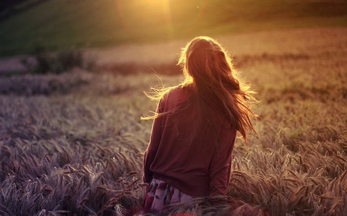 Woman with long hair in a field at sunset