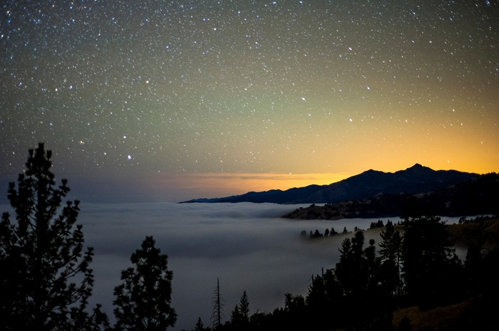 Night sky over foggy mountains and trees