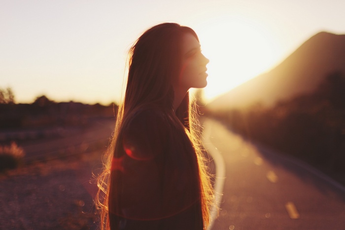 Woman in profile against the sunset on a road
