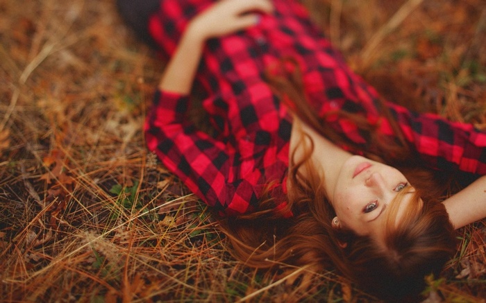 Woman in red plaid shirt lying on the ground